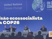 Card colorido, fundo azulado. O fundo da imagem é uma foto de um painel da COP26, o painel é azul com os logos da Nações Unidas para as Alterações Climáticas e da COP26, abaixo estão sentados em uma mesa líderes políticos de diversos países. Em destaque no centro do card o texto "Uma visão ecossocialista sobre a COP26". No canto esquerdo superior o logo do Subverta e no canto direito inferior o logo da Setorial de Meio Ambiente do Subverta.